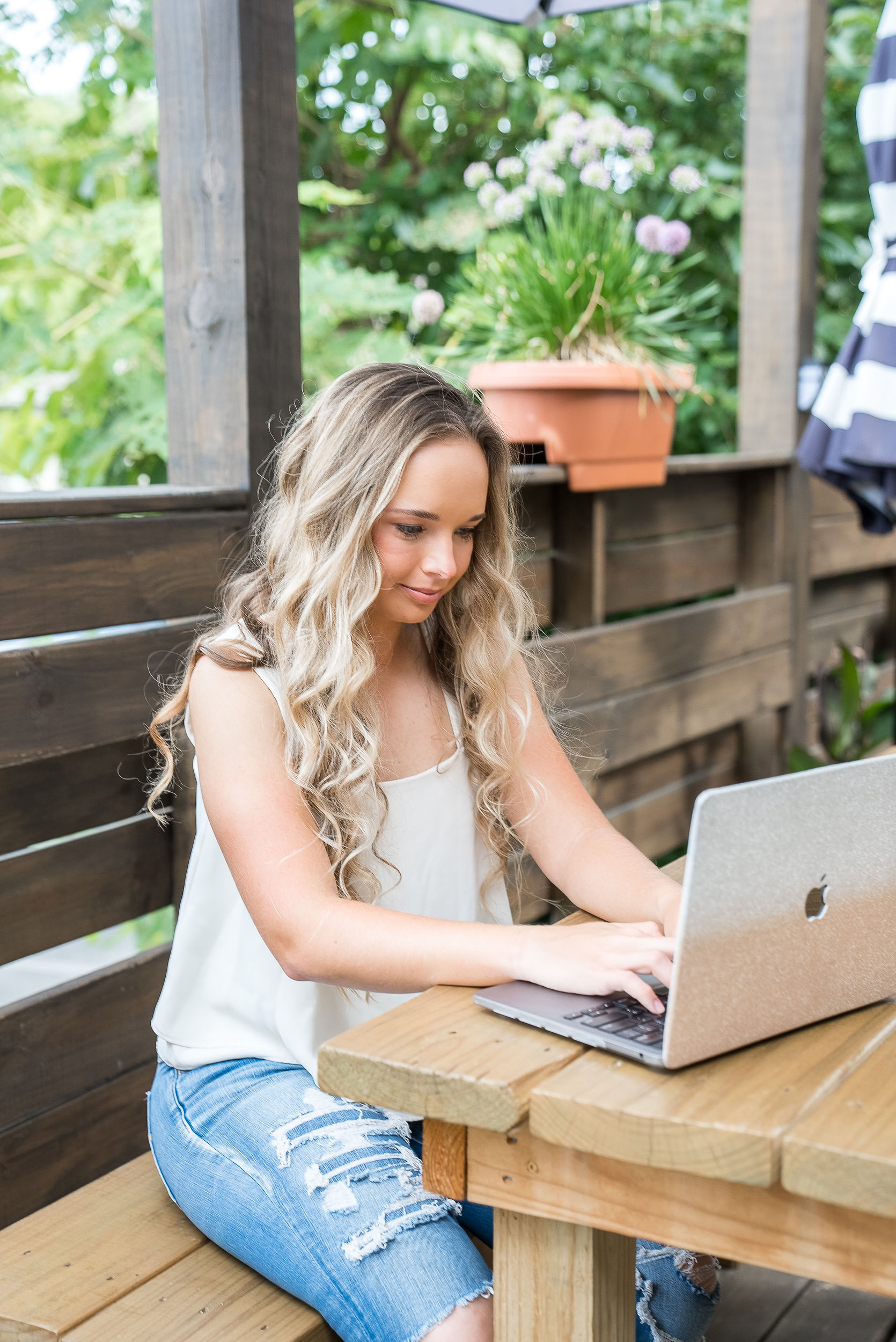 image of girl with wavey hair typing on laptop outdoors