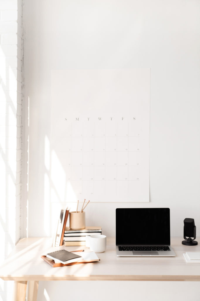 image of laptop on desk with calendar, pens, notebook